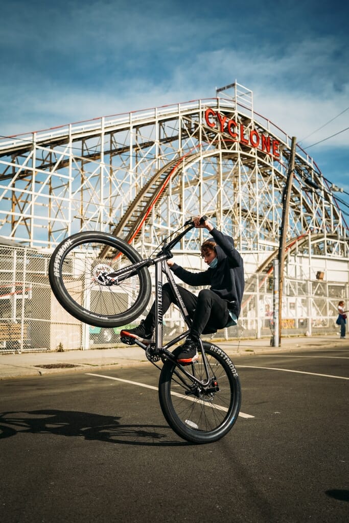 A bicyclist rides in front of Coney Island's Cyclone.